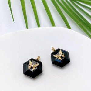 Macro view of hexagonal black stone pendant with golden butterfly and zircon inlay