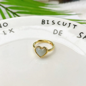 Anello regolabile a cuore dorato con pietra naturale bianca su piatto decorativo