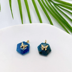 Macro view of hexagonal blue natural stone pendant with a gold butterfly and zircon detail