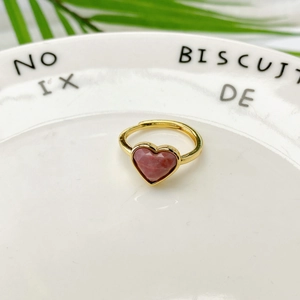 Dettaglio dell'anello con pietra rosa a forma di cuore e fascia dorata regolabile