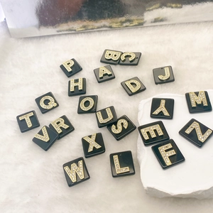 Detail von schwarzen quadratischen Anhängern mit funkelnden goldenen Strass-Buchstaben