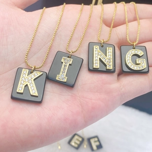 Makroaufnahme goldener quadratischer Buchstabenanhänger mit Kristallen an Goldketten