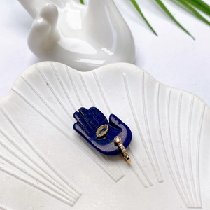 Hamsa-Hand-Anhänger aus blauem Lapislazuli mit weißen Zirkonia auf weißer Schale