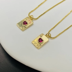 Macro detail of gold-plated Ace of Hearts poker pendant with red heart stone