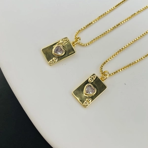 Macro detail of gold poker card pendants with pink heart stones and box chains