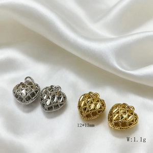 Macro detail of 12x13mm gold and silver hollow heart charms on white silk fabric
