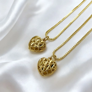 Close-up of heart-shaped 18K gold-plated pendants with lattice hollow design on silk