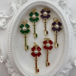 Close-up of gold-plated clover key pendants with colorful enamel and pearl accents