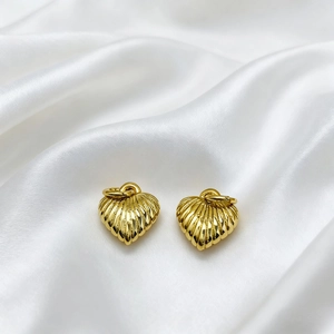 Detailed close-up of 18K gold plated shell texture heart pendants on white silk background