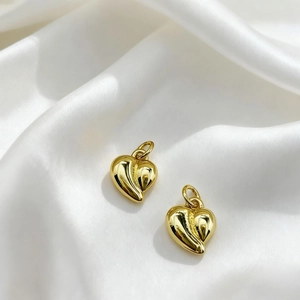 Close-up of heart-shaped 18K gold-plated pendants with unique wave texture on white silk