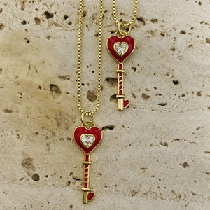 Macro shot of gold heart key pendants with red enamel finish and sparkling zircon stones