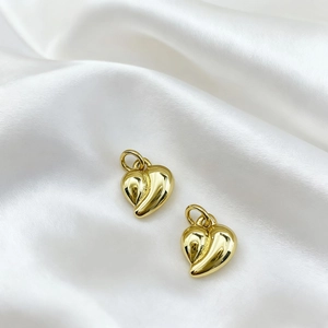 Macro shot of polished 18K gold plated heart pendant on elegant white silk background