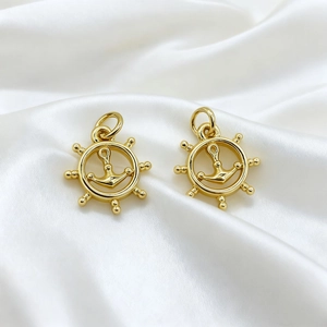 Detailed view of 18K gold plated nautical helm and anchor pendants on silk fabric