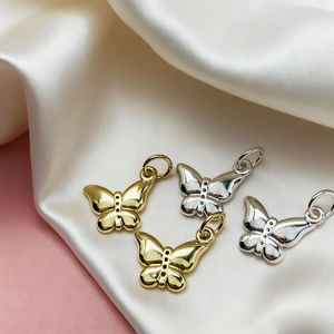 Detailed macro shot of gold and silver butterfly pendant charms for DIY jewelry making