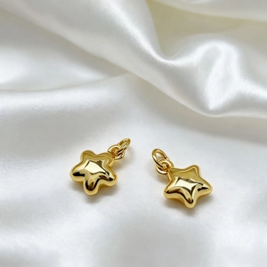Detailed view of 18K gold plated lucky star pendants on elegant white silk fabric