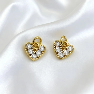 Detail of 18K gold plated heart charms with sparkling white zircons on silk background