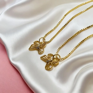 Elegant gold butterfly pendant necklace with crystal accents on a white silk background