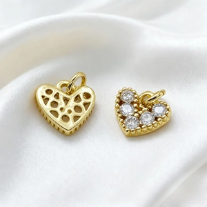 Detail of 18K gold heart pendant with zircon star and hollow geometric back on silk