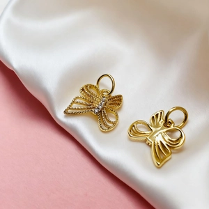Detail of golden butterfly charms with white zircon inlay and polished metallic texture