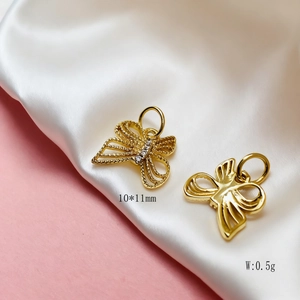 Macro detail of 10x11mm gold butterfly charms with sparkling zircons and polished finish