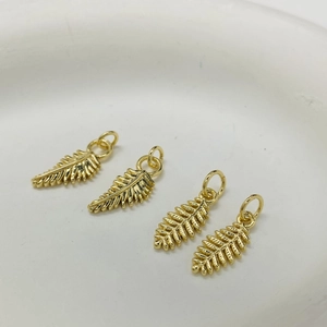 Macro detail of four gold fern leaf charms with precise engraving for DIY jewelry making
