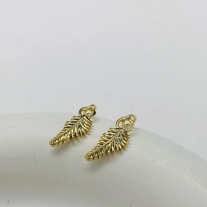 Close-up of golden feather charms with detailed texture and circular hanging rings