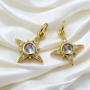 Detailed macro of two gold-plated star pendants with stones on white silk background