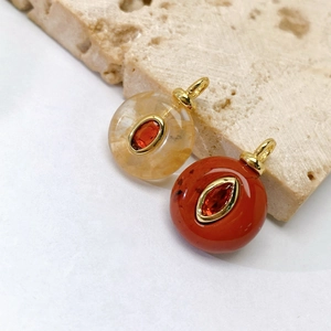 Golden round natural stone pendants with red marquise gemstone on a stone surface