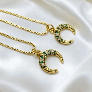 Detail macro of 18K gold plated moon pendants with green and white zircon stones