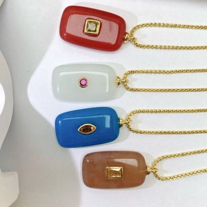 Detail of four colorful gemstone pendant necklaces with gold chain in a minimalist display