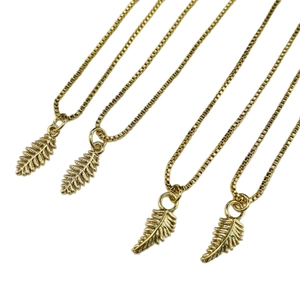 Set of four gold box chain necklaces featuring delicate fern leaf pendants on white background