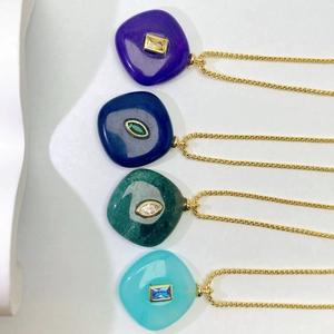 Detail of four natural stone pendants in blue, green, and purple with gold chains