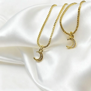 Close-up of gold box chain necklace with a crescent moon pendant set with clear zircons