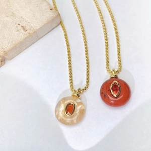 Detailed macro view of natural stone necklaces with gold frames and orange gemstones