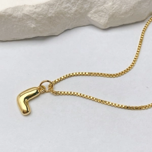 Detalle del colgante de letra L en oro de 18K con una cadena de caja altamente pulida