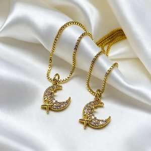 Elegant 18K gold plated moon and star pendant necklace on a white silk background