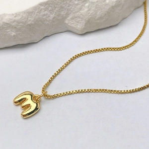 Primer plano de un collar bañado en oro con colgante de letra M y cadena veneciana fina