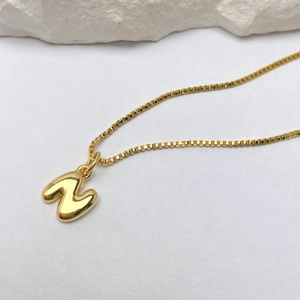 Detalle del collar con colgante de letra W dorada 3D pulida y cadena de caja fina