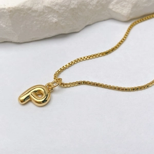 Detalle del colgante con letra p de oro pulido en una cadena de caja resistente