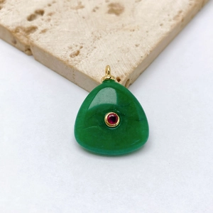 Detailed macro view of a green stone pendant with a red gemstone in golden setting