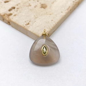 Detailed shot of triangular brown agate pendant with inlaid green gemstone and gold bail