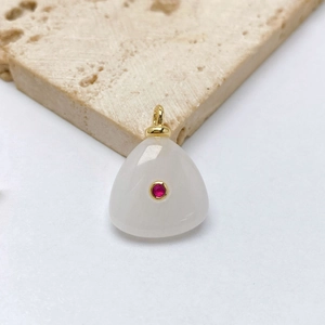 Macro shot of triangular white stone pendant with red center gem and gold bail