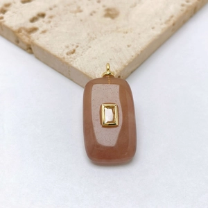 Macro shot of rectangular translucent orange stone pendant with gold setting and zircon