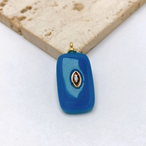 Detail of rectangular blue stone pendant with orange center gem on textured stone base