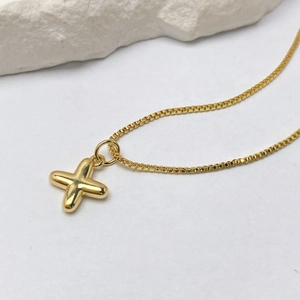 Detalle del colgante de cruz de burbuja en fina cadena veneciana de oro sobre piedra natural