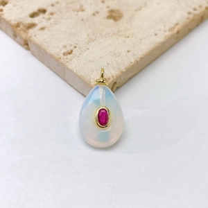 Détail macro du pendentif goutte en pierre naturelle avec gemme rouge et monture dorée