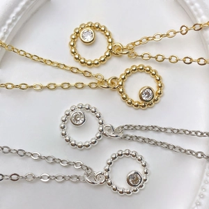 Detailed view of sun-shaped zircon pendants on gold and silver cross chains necklaces