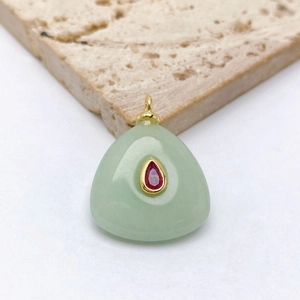 Vue macro d'un pendentif en jade vert clair en forme de goutte et zircon rouge