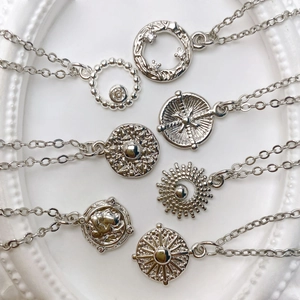 Detailed collection of silver sunburst, compass, and coin pendants on fine O-chains