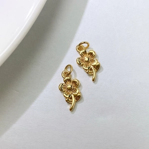 Macro detail of two golden flower pendants with polished metallic texture for DIY jewelry